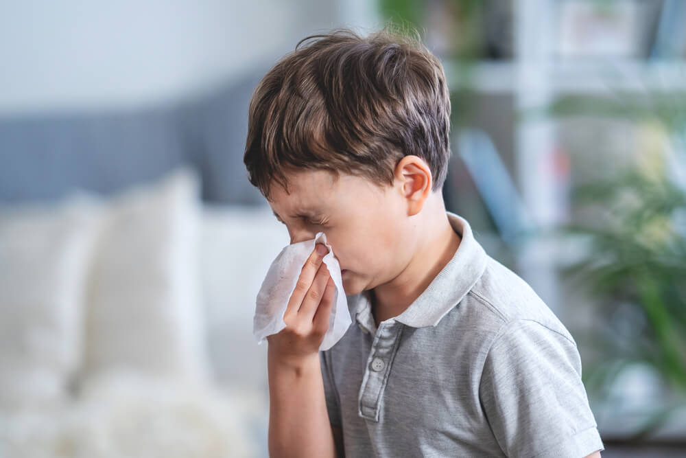 Sick boy blowing nose into tissue