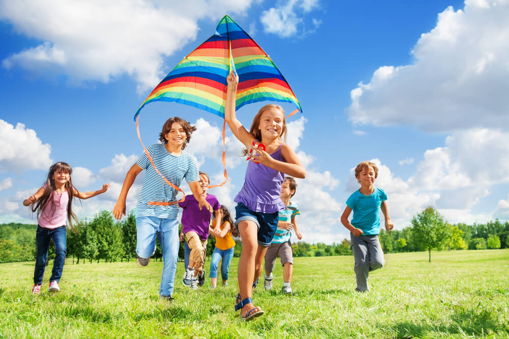 Many happy active kids run with kite in the park