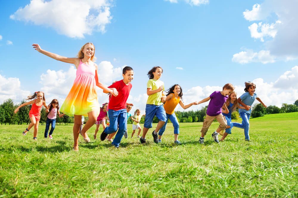 boys and girls smiling and running in the park in summer